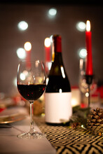Red Wine Bottle On A Christmas Holiday Festive Party Table With Wine A Glass On Red And Gold Shiny Decoration