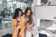 © BullRun - Women using mobile phone and drinking coffee