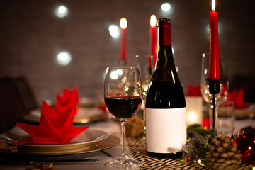 red wine bottle on a christmas holiday festive party table with wine a glass on red and gold shiny decoration