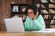 © LIGHTFIELD STUDIOS - happy african american student in eyeglasses and headphones using laptop