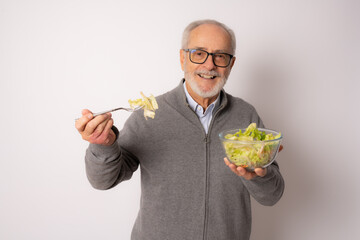 Senior happy man wearing casual sweater eating salad isolated over white background.