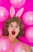 Curly-haired Girl With Open Mouth And Bunny Ears On A Pink Background With Pink Balloons