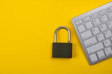 Information Protection In Cyberspace. Padlock And Keyboard On A Yellow Background. Copy Space.