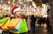 © Наталья Жукова - girl in a red santa claus hat with gifts in hands on the street of the city. Christmas mood