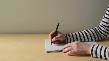 Poster - A closeup of a human hand with pen writing on a notebook