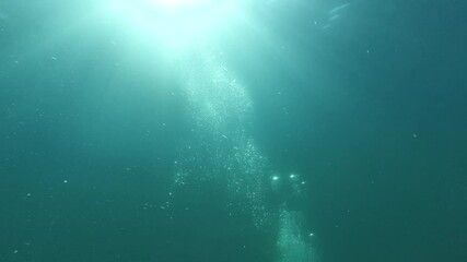 Wall Mural - underwater view of sun rays and air bubbles rising to the water surface