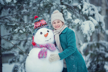 Cute girl is making a snowman. Image with selective focus