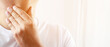 © methaphum - sore throat pain. Closeup of young man sick holding her inflamed throat using hands to touch the ill neck in blue shirt on gray background. Medical and healthcare concept. Focus red on to show pain.