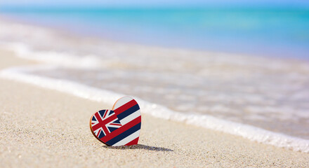 flag of the hawaiian islands in the shape of a heart on a sandy beach. the concept of the best vacat