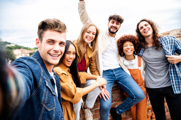 Multicultural best friends having fun taking group selfie portrait outside - Smiling guys and girls celebrating party day hanging out together on city street - Happy lifestyle and friendship concept