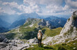 Young girl enjoying beauty of nature looking at mountains in europe. Adventure travel in Slovenia. Beautiful woman standing back on background with forest and Alps. Freedom lifestyle