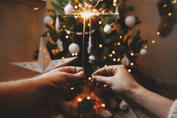 Wall Mural - Happy New Year! Couple celebrating with firework lights against christmas tree and glowing star