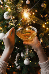 Poster - Woman celebrating with fireworks and champagne glass against christmas tree lights. Happy New Year