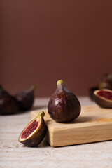 Ripe fresh Fig sliced in two on a wooden board with brown background