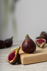 Ripe fresh Fig sliced in two on a wooden board with brown background and greenery