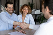 © fizkes - Joyful beautiful young family couple shaking hands with hispanic lawyer or broker, feeling thankful for professional consultation. Happy clients making agreement with realtor at office meeting.