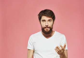 Canvas Print - emotional man in a white t-shirt hand gestures anger pink background