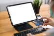 © amnaj - Close up of woman hands holding credit card and using laptop, tablet blank white screen. Online shopping concept.