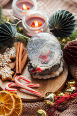 Wall Mural - A snow globe and christmas candles with branches of fir.