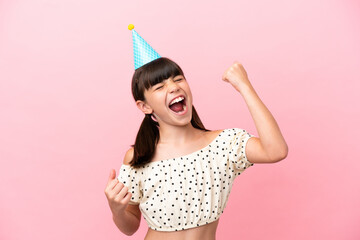 Little caucasian kid with birthday hat isolated on pink background celebrating a victory