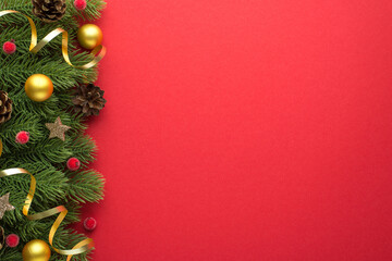 Wall Mural - Top view photo of gold small christmas tree balls pine cones red berries glowing stars and gold serpentine on pine branches on isolated red background with copyspace