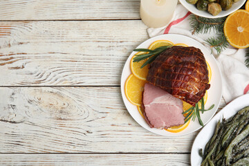 Flat lay composition with delicious ham and other festive dishes on white wooden table, space for text. Christmas dinner