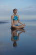 © Olga - Beach yoga practice in Bali. Lotus pose. Padmasana. Hands in gyan mudra. Meditation and concentration. Zen life. Relaxation of body and mind. Yoga retreat. Water reflection. Copy space.