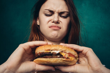 Wall Mural - woman eating hamburger fast food snack close-up