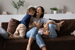© fizkes - Overjoyed mother with two kids having fun on comfortable couch at home, laughing happy mom with adorable daughter and son tickling, engaged in funny active game, spending leisure time together