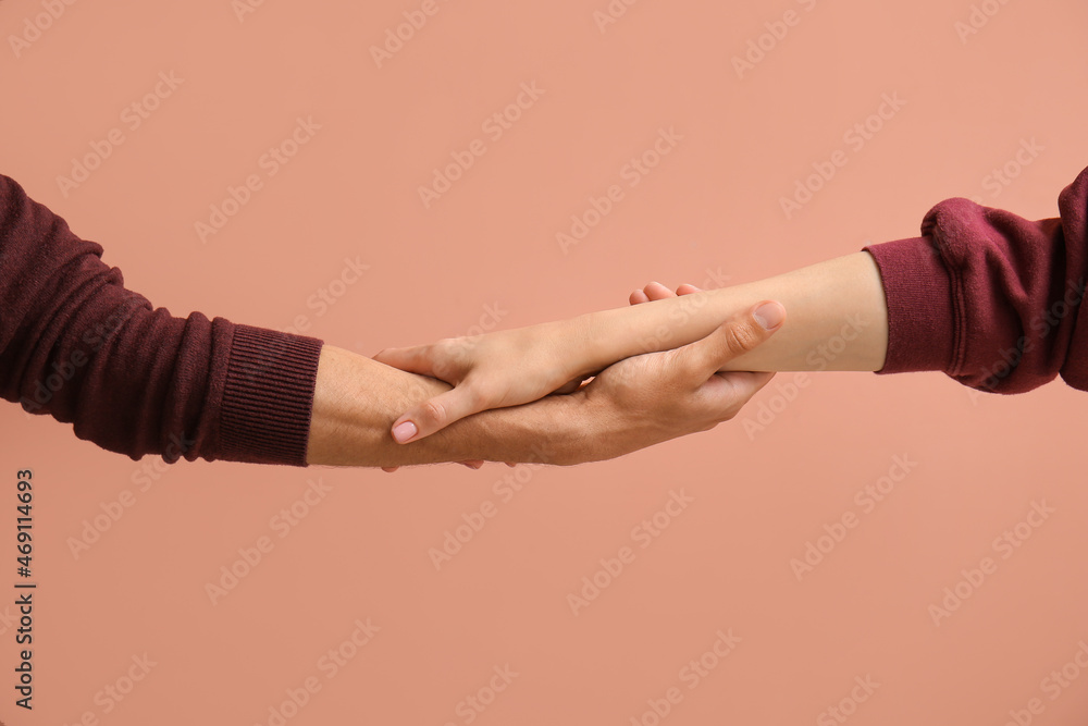 Woman and man holding hands on beige background