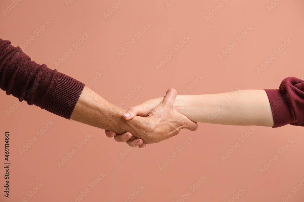 Man and woman holding hands on beige background
