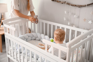 Wall Mural - Mother playing with her cute little baby in crib