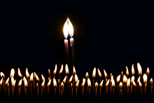 Two Thin Candles Stretch Their Lights Towards Each Other. Their Fire Merges Into One Flame. The Candles Are In Complete Darkness.
In The Foreground There Are Many Lighted And Burning Matches. 