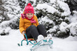 © Светлана Лазаренко - A little boy sits in a sleigh on the snow against the background of snow-covered fluffy Christmas trees. Child on a winter day.