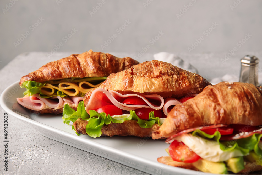 Plate with delicious croissant sandwiches on grey background, closeup
