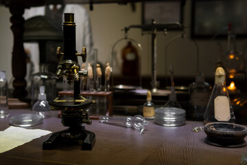 Vintage old microscope on table for science background. Medicine, alchemy, pharmacist. glass jars, flasks and tools, Selective focus