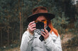 © Sergey - woman with a camera taking photos in the forest. Dressed leather hat and yellow sunglasses. Autumn day