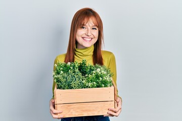 Poster - Redhead young woman holding wooden plant pot smiling with a happy and cool smile on face. showing teeth.