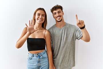 Poster - Young beautiful couple standing together over isolated background showing and pointing up with fingers number six while smiling confident and happy.