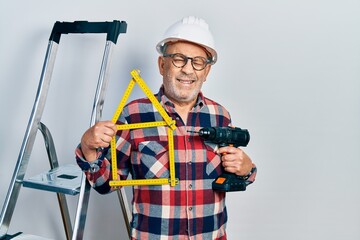 Poster - Handsome mature handyman holding screwdriver wearing hardhat by construction stairs winking looking at the camera with sexy expression, cheerful and happy face.