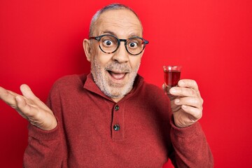 Poster - Handsome mature man drinking whiskey shot celebrating achievement with happy smile and winner expression with raised hand