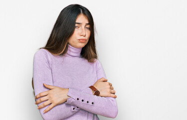 Young beautiful teen girl wearing turtleneck sweater shaking and freezing for winter cold with sad and shock expression on face