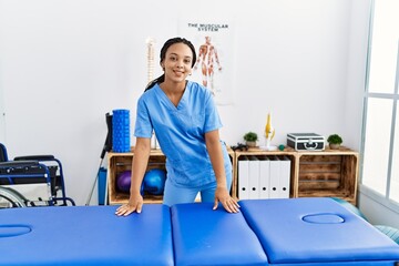 Canvas Print - Young african american woman wearing physio therapist uniform standing at clinic