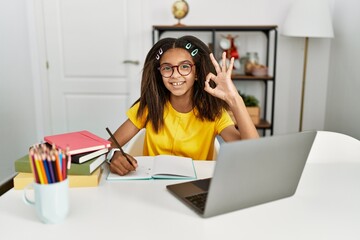 Sticker - Young african american girl doing homework at home smiling positive doing ok sign with hand and fingers. successful expression.