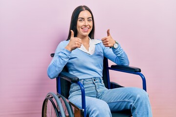 Poster - Beautiful woman with blue eyes sitting on wheelchair success sign doing positive gesture with hand, thumbs up smiling and happy. cheerful expression and winner gesture.