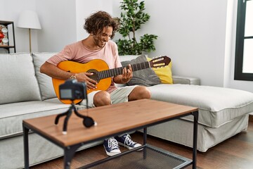 Canvas Print - Young hispanic man recording with camera playing classical guitar at home.