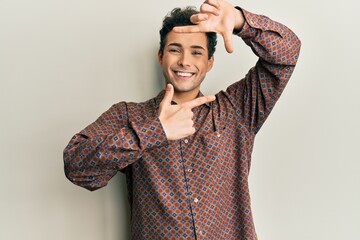 Handsome hispanic man wearing casual clothes smiling making frame with hands and fingers with happy face. creativity and photography concept.