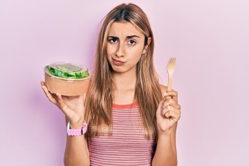 Canvas Print - Beautiful hispanic woman eating salad skeptic and nervous, frowning upset because of problem. negative person.