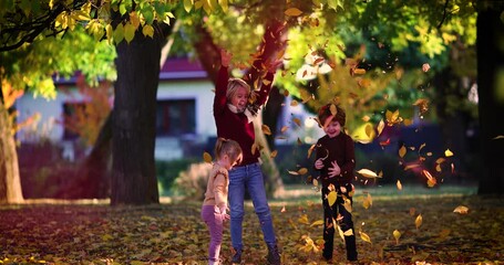 Wall Mural - happy kids playing in autumn park, having fun and throwing leaves at sunny day