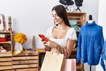 Poster - Young hispanic woman using smartphone shopping at clothing store